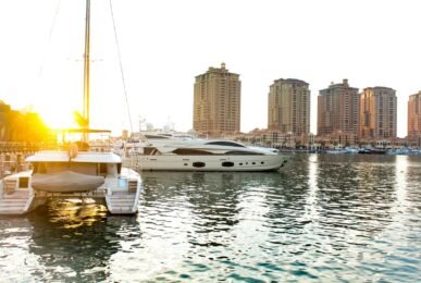 Scenic view of yachts docked at Doha marina with striking skyscrapers at sunset.